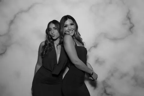 Two guests posing for a black and white photo booth portrait against a marble backdrop