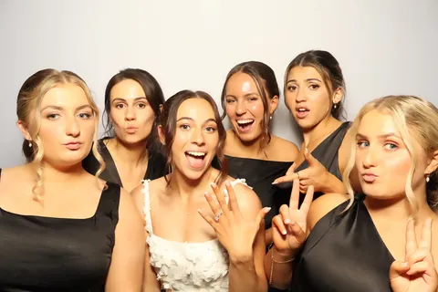 Wedding guests smiling together against a white photo booth backdrop