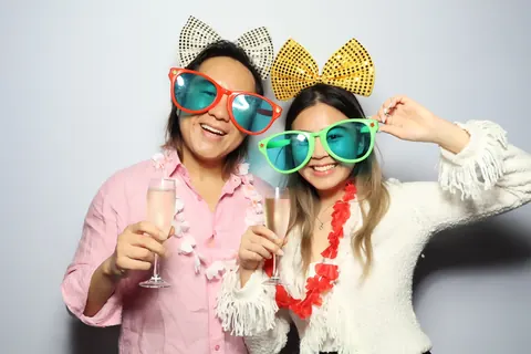 Two guests wearing bow props and colourful glasses at a corporate event at Hotel Steyne Manly