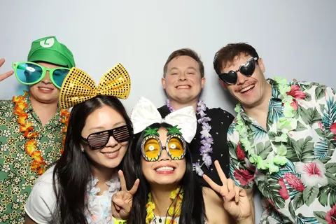 Guests posing in colourful garlands and playful hats at a corporate event at Hotel Steyne Manly