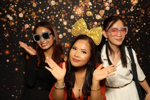 Three guests wearing oversized glasses and a gold bow at a corporate event at The William Inglis Hotel