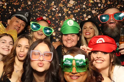 Guests wearing colourful props against a sparkling black backdrop at a corporate event at The William Inglis Hotel