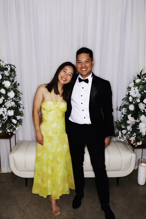 Couple posing with ivory drapes, white florals and lounge seating