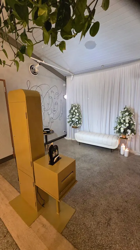 Gold Photo Booth beside ivory drapes, white florals and lounge seating