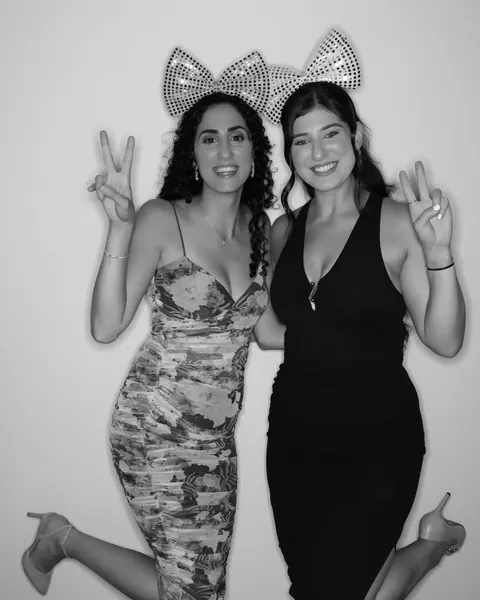 Two guests wearing bow props in a black and white Gold Booth portrait