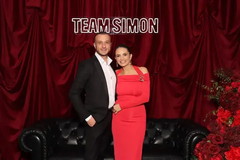 Couple posing in front of red drapes with lounge seating