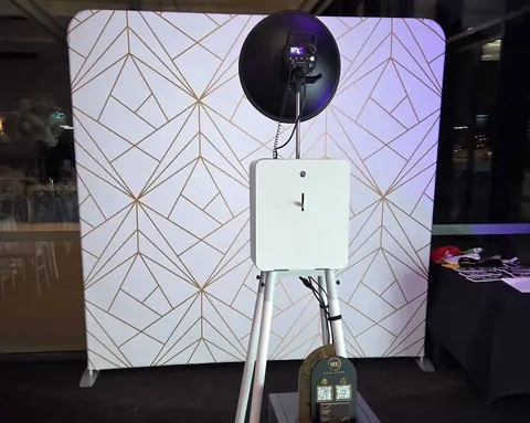 Open Air Photo Booth with a white and gold geometric backdrop
