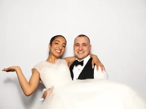 Bride and groom posing with her wedding dress spread in front