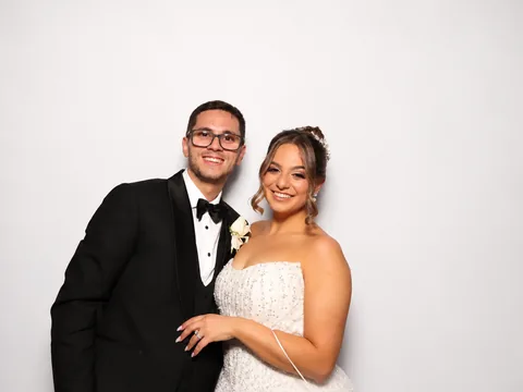 Bride and groom smiling together against a white backdrop
