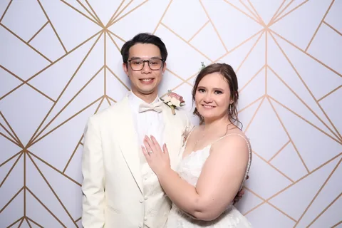 Wedding couple posing against a gold geometric backdrop