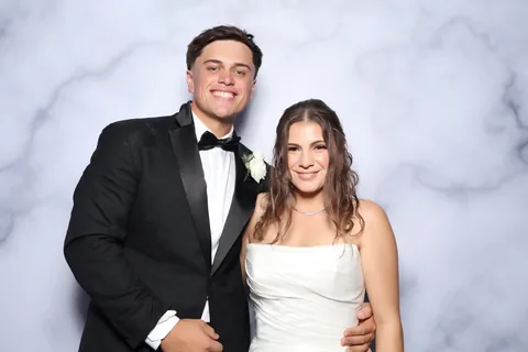 Bride and groom smiling against a marble-patterned backdrop
