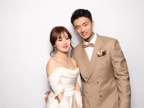 Wedding couple posing together against a white backdrop